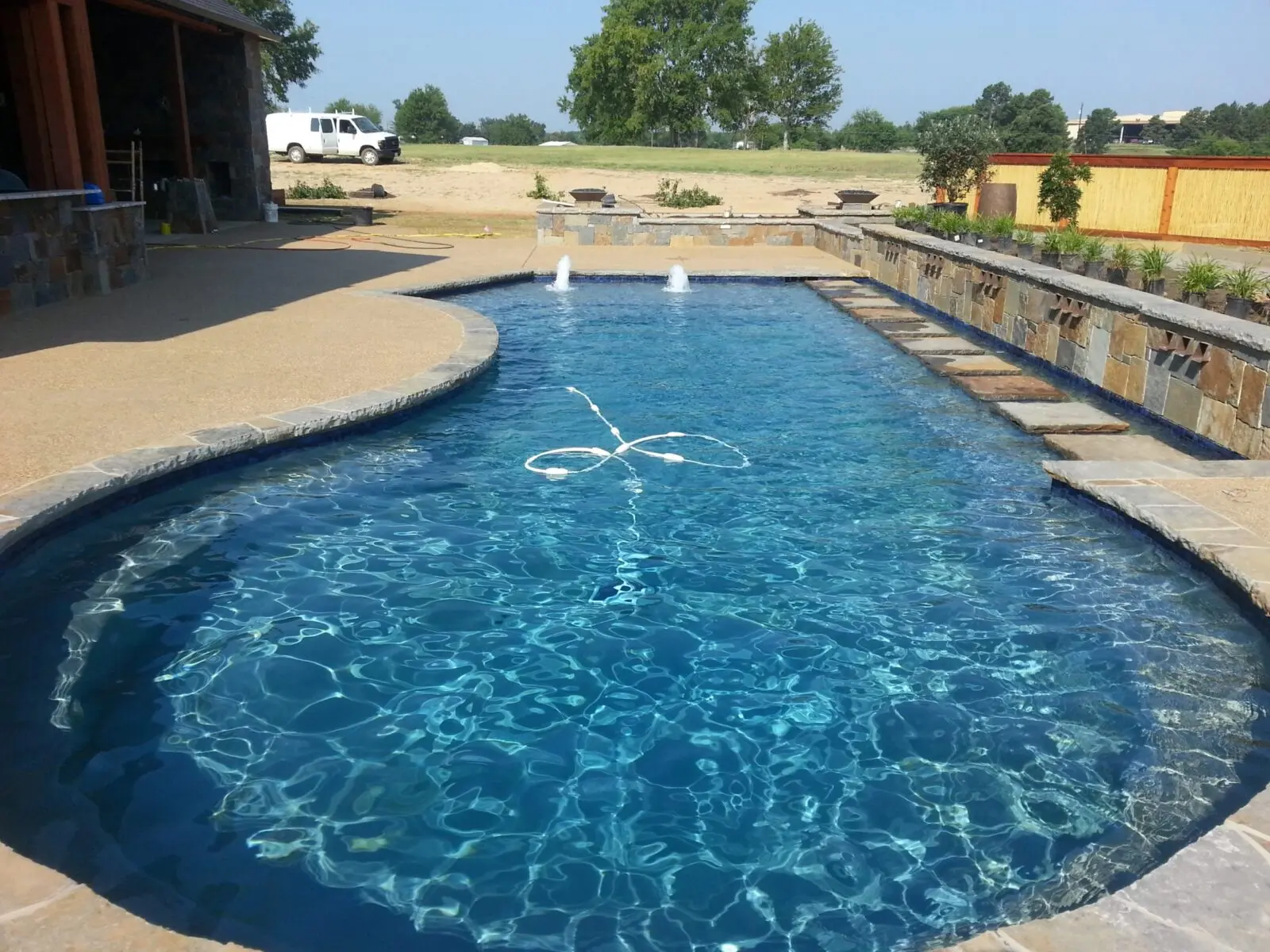 Custom gunite pool with a stacked stone retaining wall and stepping stones