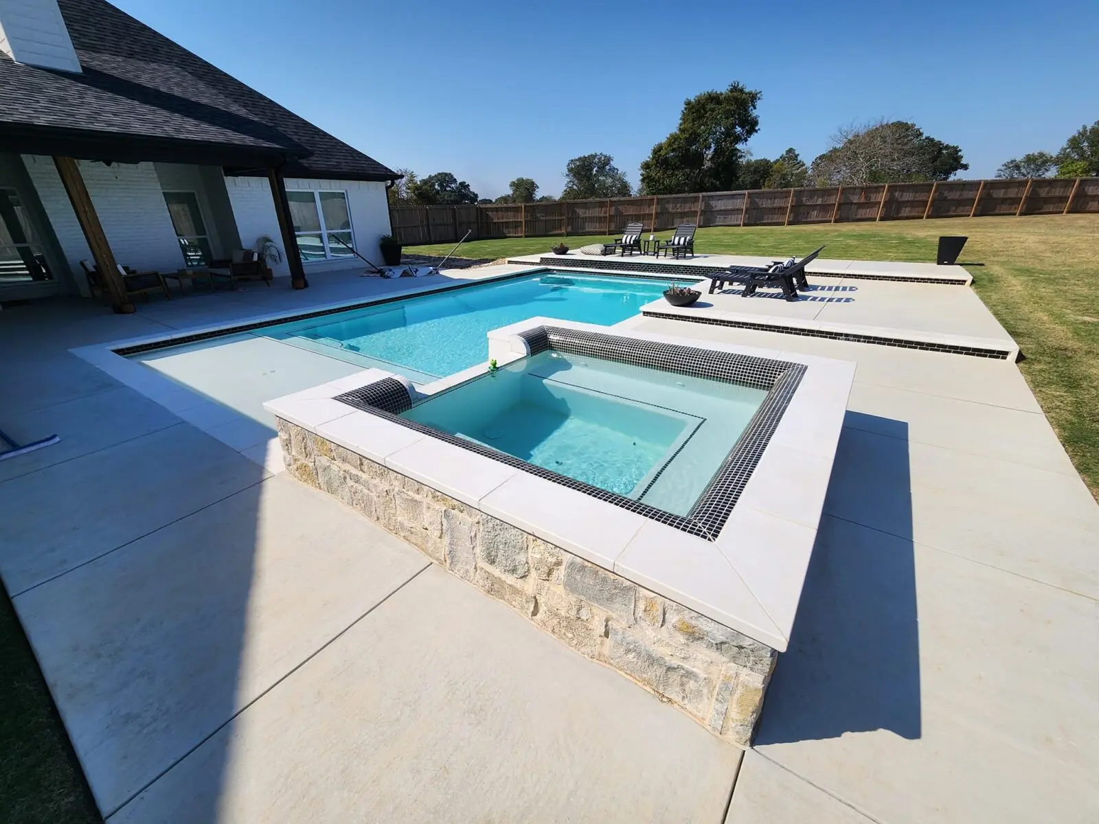 Raised stone spa joined to a custom rectangular pool