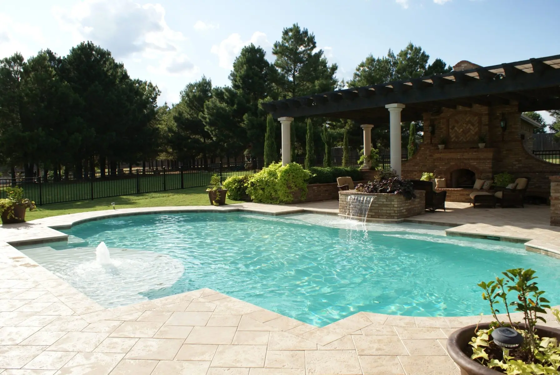 Custom pool with a travertine deck, a pergola and an outdoor fireplace